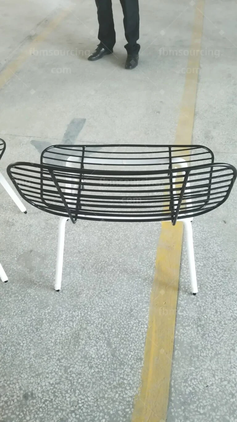 Black wire-frame chair on white legs at the inspection