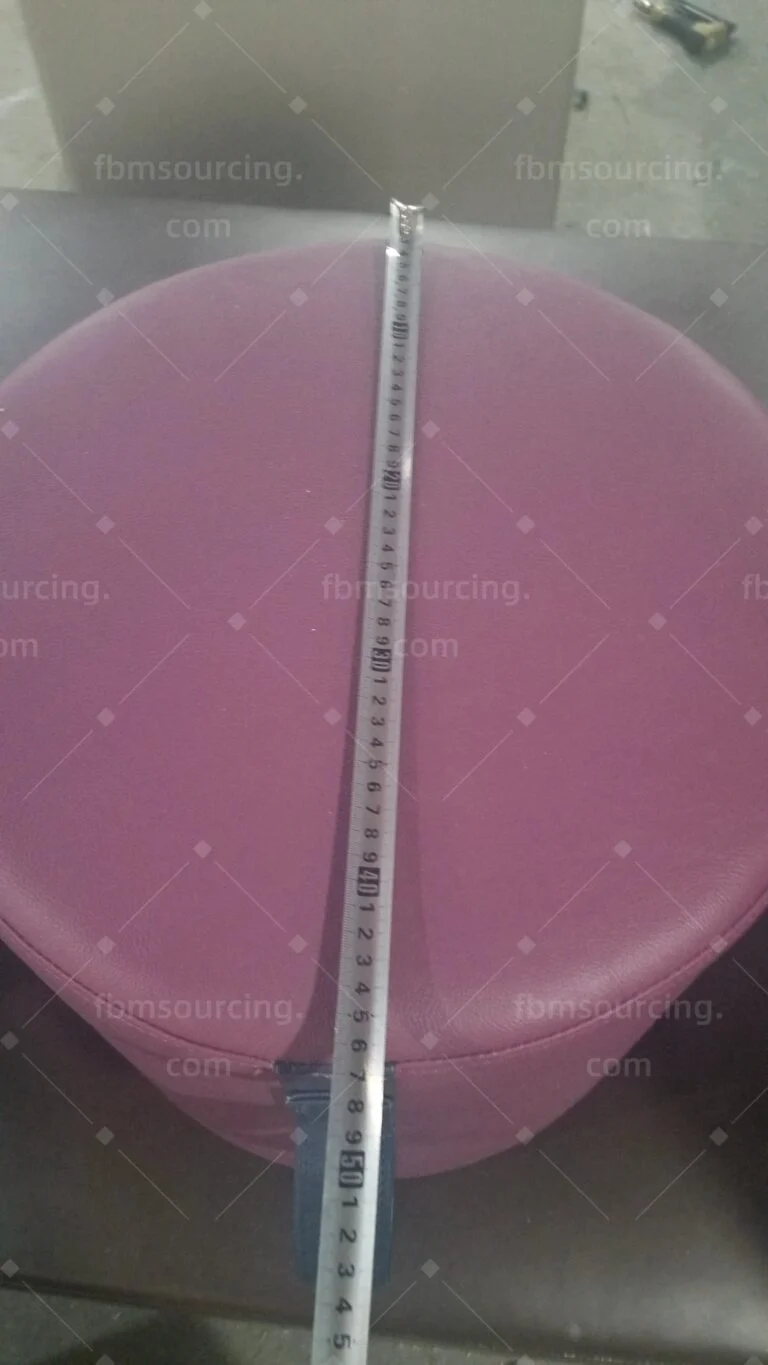 Pink upholstered stool top measured with a tape