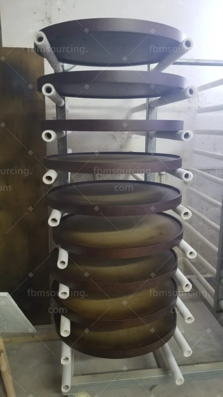 Round dark tabletops stacked on a rack